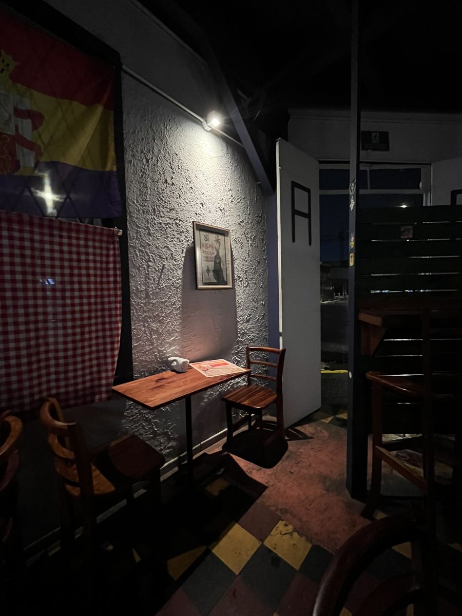 Rincón con mesa de madera, mantel a cuadros y bandera en la pared